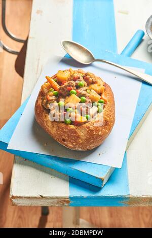 Gulasch serviert in einer Brotschale, einem traditionellen Rindfleischeintopf der ungarischen Küche. Stockfoto