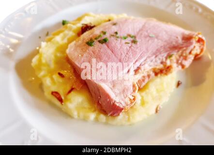 Braten Sie Schinkenscheibe mit Kartoffelpüree auf weißem Teller. Stockfoto
