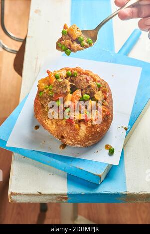 Gulasch serviert in einer Brotschale, einem traditionellen Rindfleischeintopf der ungarischen Küche. Stockfoto