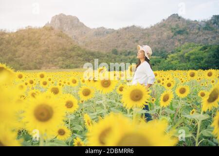 Glückliche Frau im Sonnenblumenfeld lächelt mit Glück wegen gesunder Nahrung. Happy People, Health Care und Agriculture Business Concept. Glücklicher Bauer oder Stockfoto