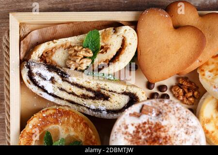 Apfel- und Mohn-Strudel, Kekse und duftender Zimtkaffee auf einem rustikalen Holztablett. Draufsicht, Nahaufnahme. Selektiver Fokus. Stockfoto