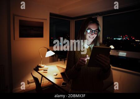 Kaukasische Geschäftsfrau Scrollen auf digitalen Tablet arbeiten spät an Übernachtung in der Wohnung Stockfoto