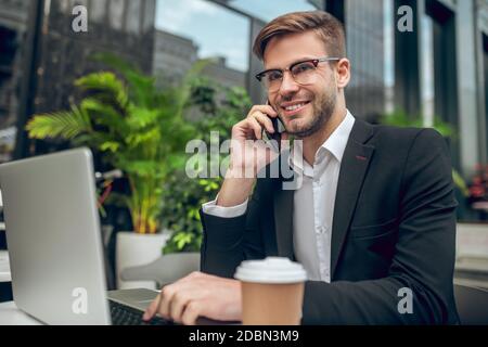 Hübscher junger Geschäftsmann, der am Telefon spricht und lächelt Stockfoto