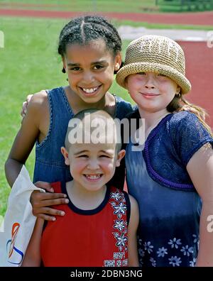 Porträt von Freunden mit schwarzen afroamerikanischen Kind mit Arm Um weißen Freund Stockfoto