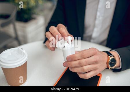Nahaufnahme der hände von mans, die kabellose Kopfhörer halten Stockfoto