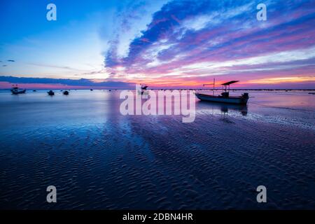 Landschaft farbenfroher Himmel und Fischerboote vor Anker, während die Flut am Abend am Strand von Pakarang, Takuapa, Phang Nga, Thailand sinkt Stockfoto