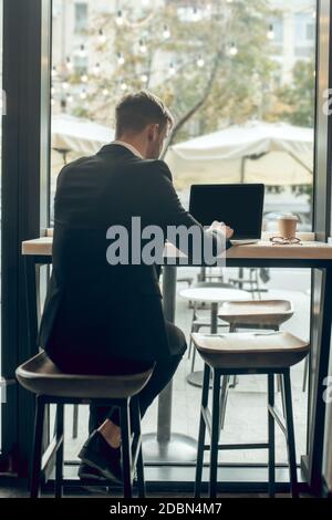 Junger Geschäftsmann sitzt in einem Café und arbeitet an der Notebook Stockfoto