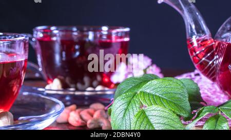 Englischer Tee. Roter heißer Hibiskus-Tee in einem Glas-Becher. Teestunde: tasse Tee, Karkade, Karkade, Rooibos. Orientalisch, gemütlich, Zeremonie, Tradition, Japaner, belaubt, Stockfoto