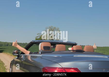 Ein älteres Paar fährt mit einem Luxus-Cabriolet in die Natur Stockfoto