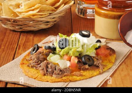 Tostadas aus Rindfleisch und Bohnen mit Cheddar-Käse, schwarzen Oliven, saurer Sahne und Guacamole Stockfoto