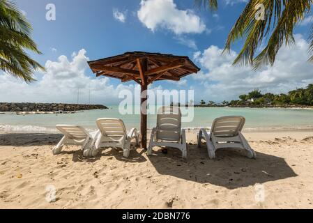 Ferienhäuser Konzept - vier Stühlen und Holz- Palapa Sonnendach Sonnenschirm am tropischen Strand - der Karibikinsel Guadeloupe Stockfoto