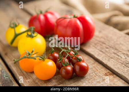 Eine Auswahl von ganzen Erbstück Tomaten auf einem hölzernen Hintergrund angezeigt. England GB Stockfoto