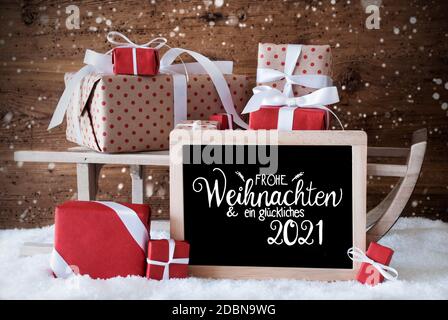 Tafel mit deutscher Kalligraphie Frohe Weihnachten und ein glückliches 2021 bedeutet Frohe Weihnachten und EIN glückliches 2021. Schlitten Mit Weihnachtsgeschenk Und Pr Stockfoto