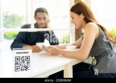 Asiatische Kunden suchen Online-Menü nach Scan QR-Code. Der Kunde saß auf einem Tisch mit sozialer Distanz, um nach dem Coronavirus im Restaurant einen neuen normalen Lebensstil zu erhalten Stockfoto