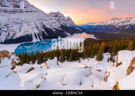 Die Sonne untergeht und der Himmel leuchtet mit Farbe über einem eisbedeckten Peyto-See im Banff-Nationalpark. Stockfoto