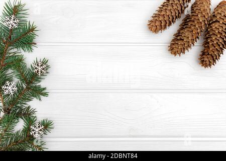 Zapfen und Kiefernzweige mit Schneeflocken-Ornamenten auf weißem Holzhintergrund. Vorlage für Neujahrskarte, Platz zum Kopieren Stockfoto