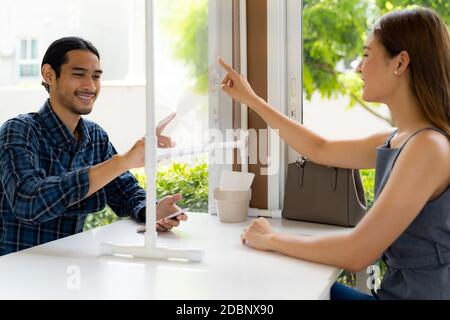 Asiatische Kunden berühren auf virtuellen Bildschirm, um Menü auf Social Distanzing Tabelle für neue normale Lebensweise im Restaurant nach Coronavirus covid-19 pa wählen Stockfoto