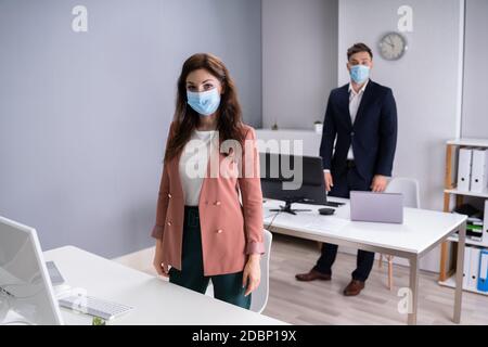 Mitarbeiter Im Büro, Die Medizinische Masken Tragen Und Social Distancing Protocols Befolgen Stockfoto