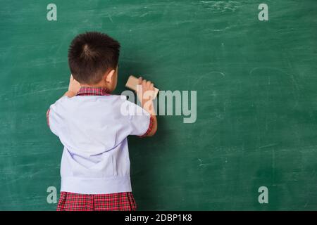 Zurück zur Schule. Zurück von asiatischen niedlichen kleinen Kind junge Kindergarten Vorschule in Schüler Uniform wischen sauber oder löschen Kreide auf grünen Schule Tafel w Stockfoto