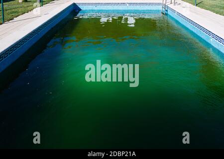 Unbeaufsichtigter Außenpool im Winter, mit grünem Wasser von Algen überfallen. Stockfoto