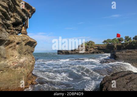 Tempel an der Küste des Indischen Ozeans in der Nähe des heiligen balinesischen Tempels Tanah Lot. Pura Batu Bolong am Rande einer Klippe an der Küste mit Loch im Felsen Stockfoto