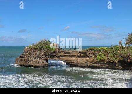 Küste des Indischen Ozeans in der Nähe des heiligen balinesischen Tempels Tanah Lot. Pura Batu Bolong am Rande einer Klippe an der Küste mit Loch in den Felsen. Heiliger Ort f Stockfoto