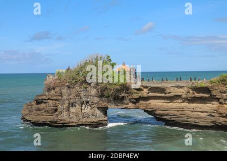 Küste des Indischen Ozeans in der Nähe des heiligen balinesischen Tempels Tanah Lot. Pura Batu Bolong am Rande einer Klippe an der Küste mit Loch in den Felsen. Heiliger Ort f Stockfoto