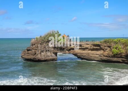 Küste des Indischen Ozeans in der Nähe des heiligen balinesischen Tempels Tanah Lot. Pura Batu Bolong am Rande einer Klippe an der Küste mit Loch in den Felsen. Heiliger Ort f Stockfoto