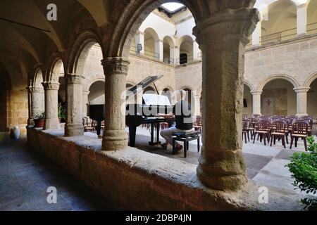Pianist spielt einen Flügel im Kreuzgang des Alte Kirche von San Francesco in Alghero Stockfoto