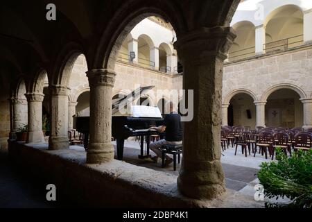 Pianist spielt einen Flügel im Kreuzgang des Alte Kirche von San Francesco in Alghero Stockfoto