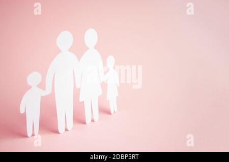 Papierfamilie auf hellrosa Hintergrund, Familienhaus, Pflegepflege, psychische Gesundheit der Familie, Bildungskonzept Homeschool. Stockfoto