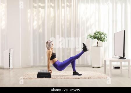 Junge Frau Ausübung Schritt Aerobic zu Hause vor tv Stockfoto