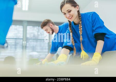 Reinigungspersonal, das Schreibtische in einem Bürogebäude abwischt Stockfoto