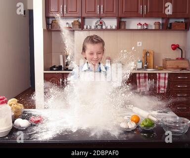 kleines Mädchen trägt dazu bei, in einer chaotischen Küche Backen Stockfoto