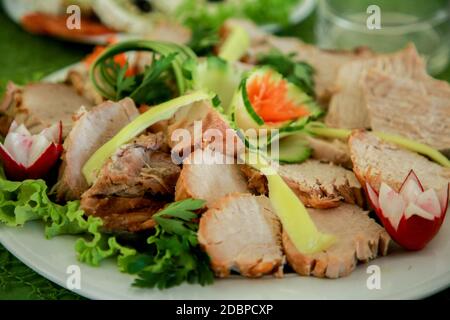Schweinelende mit Gurke und Rettichsalat. Gegrillter Schweinehals serviert mit in Scheiben geschnittenen Gurken, gegrilltes Schweinefleisch auf einem weißen Teller Stockfoto