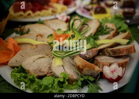 Schweinelende mit Gurke und Rettichsalat. Gegrillter Schweinehals serviert mit in Scheiben geschnittenen Gurken, gegrilltes Schweinefleisch auf einem weißen Teller Stockfoto