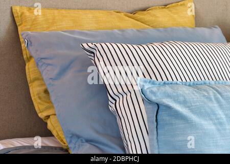 Nahaufnahme von gelben und hellblauen Kissen in einer Reihe auf dem Bett, moderne Retro-Dekoration für zu Hause, pastellfarbene helle Farben bunten hellen Hintergrund Stockfoto