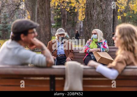 Montreal, CA - 7. November 2020: Älterer Mann und Frau mit Gesichtsmasken auf einer Bank in einem Park, während der Covid-19 Pandemie Stockfoto