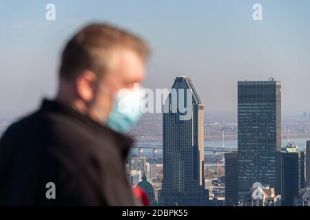 Montreal, CA - 10 November 2020 : Mann trägt eine Maske inmitten Coronavirus Ausbruch Blick auf Montreal Skyline von der Spitze des Mount Royal Stockfoto