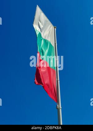 Bulgarische Flagge winkt auf blauem Himmel Hintergrund. Der Standort ist Obzor, Bulgarien. Flagge Bulgariens gegen den klaren Himmel. Stockfoto