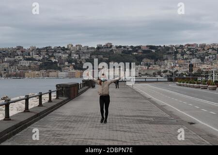 Neapel, Italien. November 2020. Eine Frau mit Schutzmaske geht an der Strandpromenade der Stadt Neapel. Die Region Kampanien befindet sich in der roten Zone mit den höchsten Beschränkungen, um die Ausbreitung der Covid-19-Krankheit zu stoppen. Kredit: Unabhängige Fotoagentur/Alamy Live Nachrichten Stockfoto