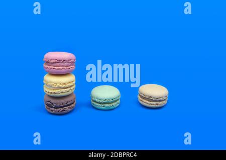 Bild von ein paar Macarons in verschiedenen Farben, auf einem Tisch und blauem Hintergrund gestapelt, mit Kopierraum Stockfoto