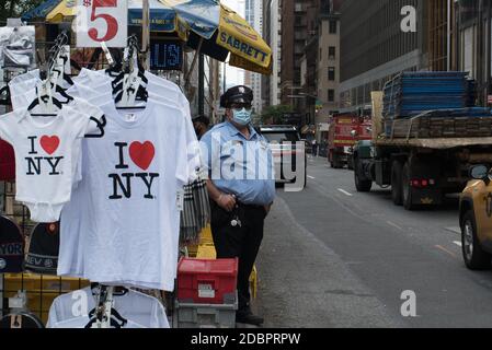 Manhattan, New York. 01. Oktober 2020. Ein Wachmann trägt eine Maske neben einem Touristenstand, der T-Shirts verkauft. Stockfoto