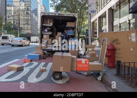 Manhattan, New York. 08. Oktober 2020. Ein FedEx-Arbeiter mit einer Maske lädt Pakete aus seinem Lieferwagen in Midtown. Stockfoto