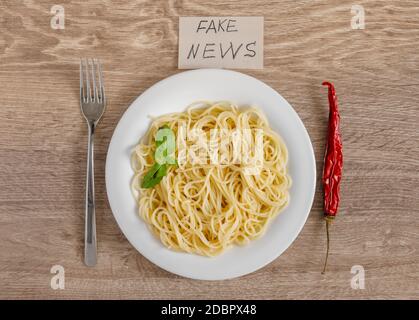 Spaghetti mit einem Zweig von Basilikum und Chili als Ein Fake-News-Konzept Stockfoto