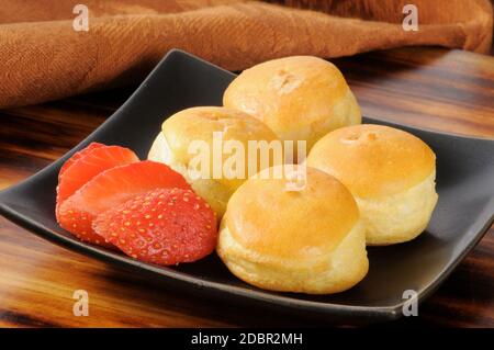 Ein Teller Mini-Sahne-Puffs mit Erdbeeren Stockfoto