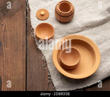 Leere runde braune Platte, die auf einer grauen LeinenServiette steht, Holzhintergrund aus alten Bretter, Draufsicht Stockfoto