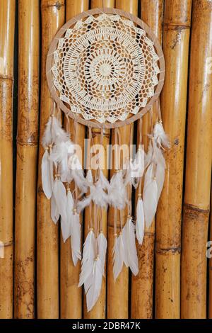 Traumfänger, verziert mit weißen Federn und Holzperlen, auf einer Holzoberfläche. Traumfänger mit Holzkreis. Gestricktes Native American Amulett w Stockfoto