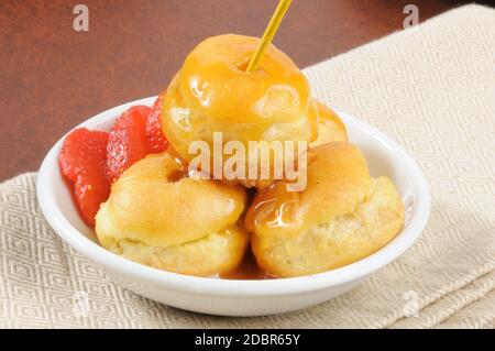 Mini-Sahne-Puffs mit Karamell und Erdbeeren gekrönt Stockfoto