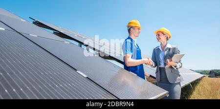 Bauarbeiter und Investor im Solarkraftwerk, der nach Abschluss des Projekts die Hände schüttelt Stockfoto